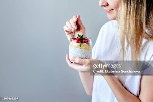 close-up of a young woman in a white shirt with chia seed pudding with berries and fruit - mousse dessert 個照片及圖片檔