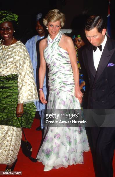Prince Charles, Prince of Wales and Diana, Princess of Wales, wearing a chiffon halterneck evening gown designed by Catherine Walker, walk with...