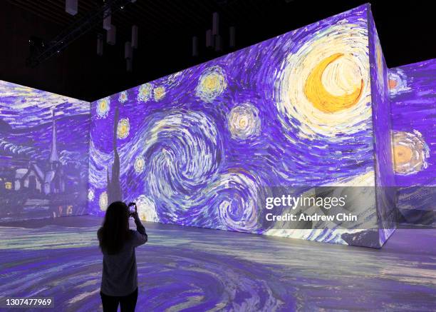 Jessica Wilson wearing protective face mask uses her mobile phone to take a picture of Vincent Van Gogh’s "Starry Night" during a media preview of...