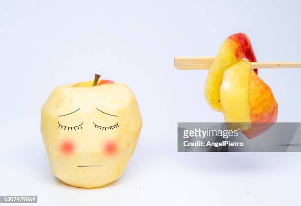 peeled apple with the skin on the hanger - ashamed apple - food with humor. - éplucher photos et images de collection