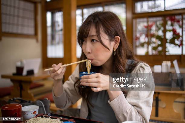 young woman eating soba in japanese restaurant - soba stock pictures, royalty-free photos & images