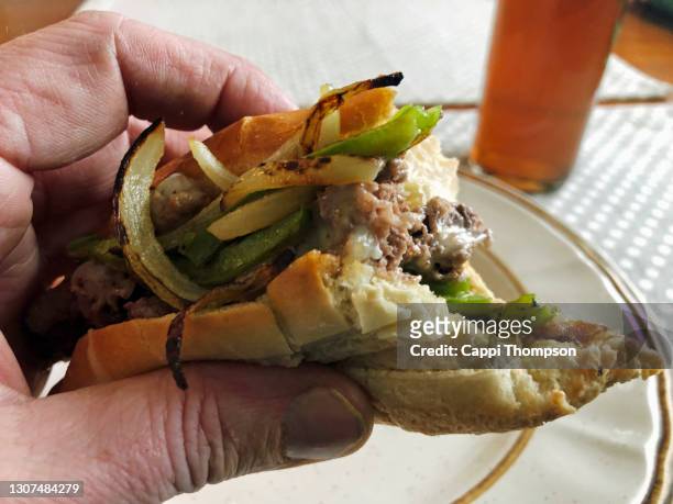 steak and cheese submarine sandwich in man's hand - submarine sandwich imagens e fotografias de stock