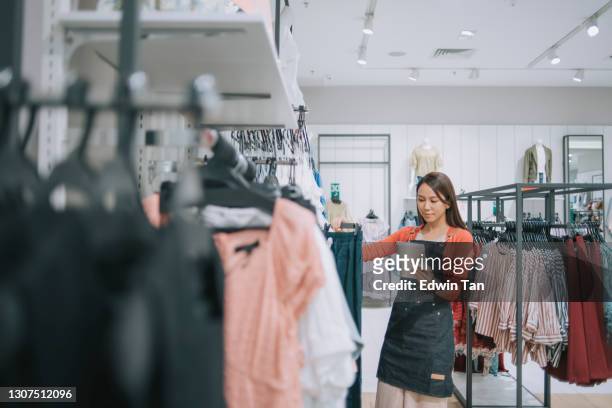 asian chinese female boutique shop clothing store owner checking stock with digital tablet - retail stock pictures, royalty-free photos & images