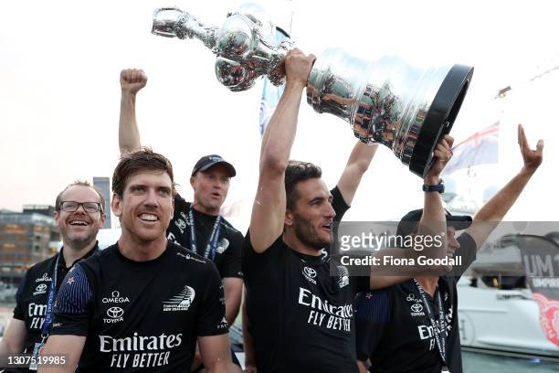 Emirates Team New Zealand members Peter Burling, Blair Tuke and Glenn Ashby pose with the "Auld Mug" trophy after winning race and the America's Cup...