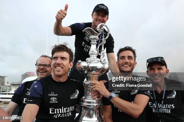Emirates Team New Zealand members Peter Burling, Blair Tuke and Glenn Ashby pose with the "Auld Mug" trophy after winning race and the America's Cup...