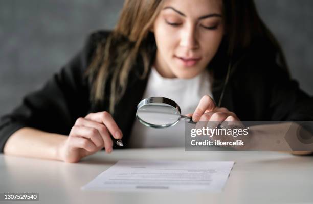 businesswoman reading a legal document carefully using magnifying glass before signing - contracting stock pictures, royalty-free photos & images