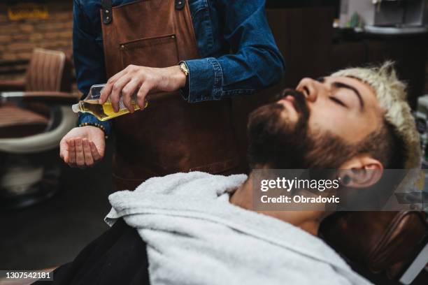 barber giving a haircut in his shop - beard stock pictures, royalty-free photos & images