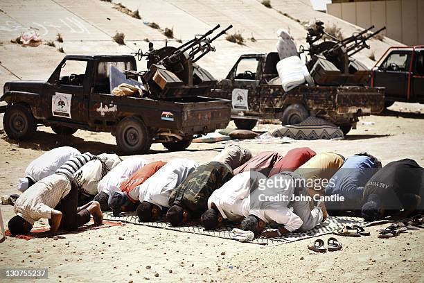 Fighters pray next to their gun trucks at an intersection on September 6, 2011 in Misrata, Libya. Fighting in Libya has ceased following the killing...