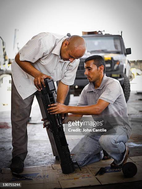 Mechanics work on a machine gun part which will be fitted to a gun truck on September 5, 2011 in Misrata, Libya. Fighting in Libya has ceased...