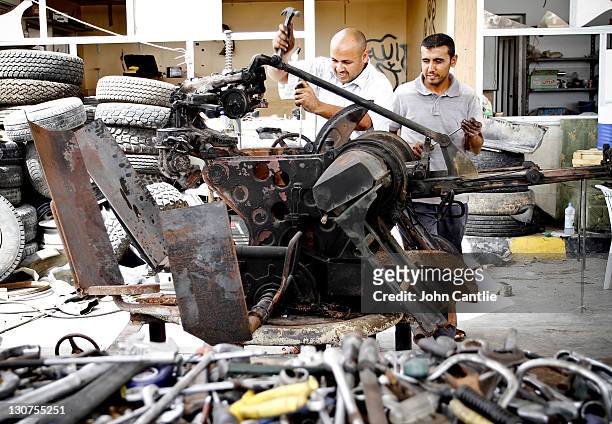 Mechanics work on an anti-aircraft gun recovered from a destroyed rebel vehicle on September 4, 2011 in Misrata, Libya. Fighting in Libya has ceased...