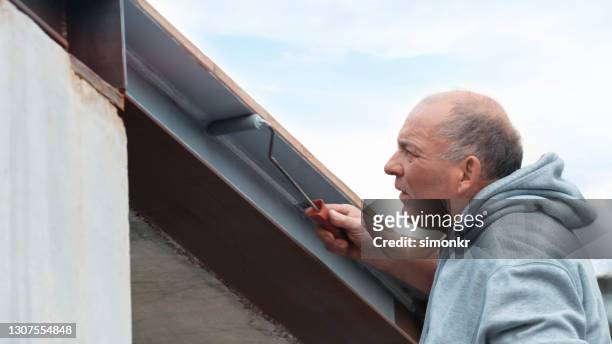 man painting beam using paint roller - painted roof stock pictures, royalty-free photos & images