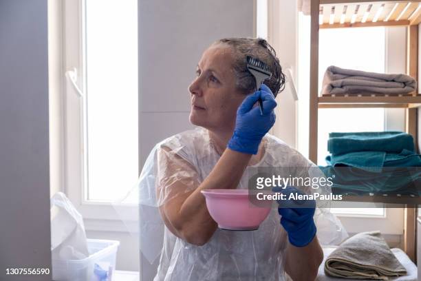 senior woman dyeing her hair at home - senior colored hair stock pictures, royalty-free photos & images