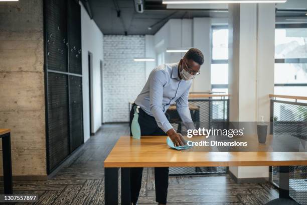 sanitizing desk surface during covid-19 pandemic - clear desk stock pictures, royalty-free photos & images