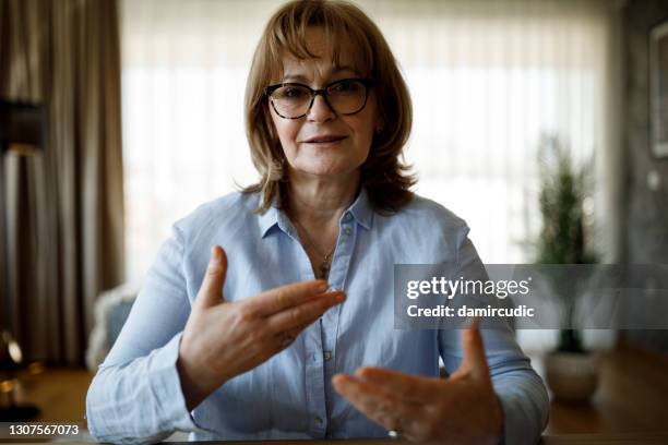 portrait of smiling confident senior woman looking at camera and talking - hands explaining stock pictures, royalty-free photos & images
