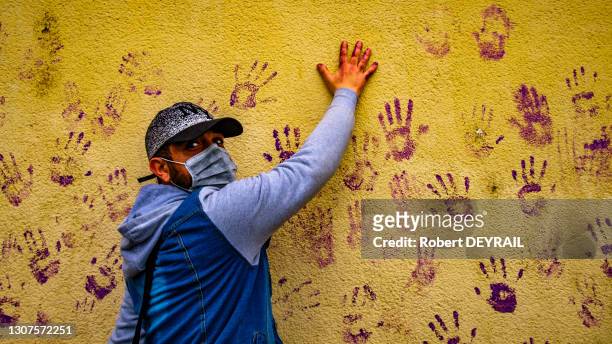 En signe de solidarité un homme pose sa main sur une des Khomsas laissées par les mains des manifestantes sur un mur lors de la manifestation...