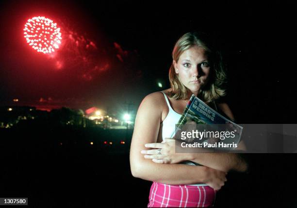 Girl cries July 29, 2000 while holding a press clipping of Bradd Pitts and Jennifer Aniston''s wedding in Malibu, CA. Behind her is a firework...