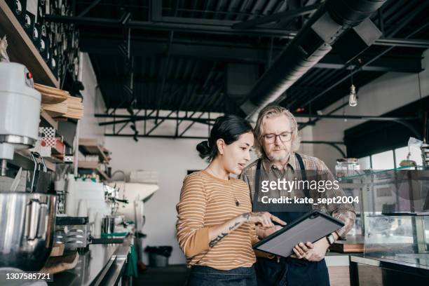 female and male entrepreneurs discussing while standing  in modern coffee shop - vendor management stock pictures, royalty-free photos & images