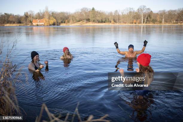 adult hobby group enjoying in ice cold lake water - woman ice stock-fotos und bilder