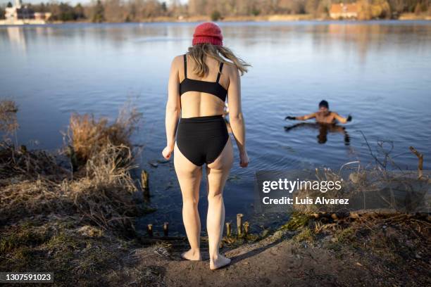 woman going for a swim in lake on a winter day - donne bionde scalze foto e immagini stock