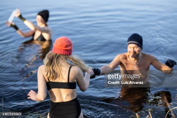 group of people going swimming in ice cold lake - eis baden stock-fotos und bilder