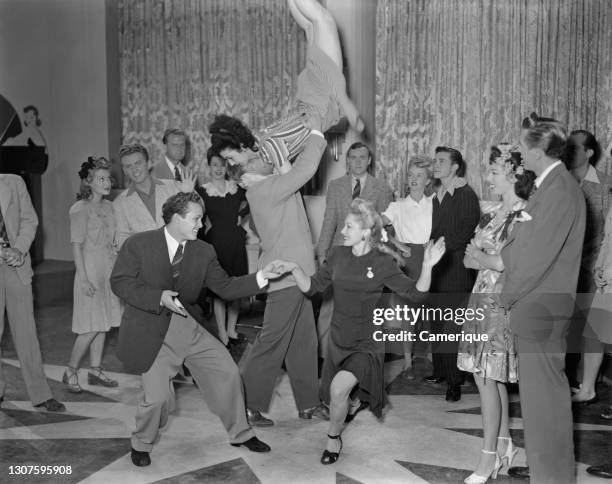 Two couples dancing the Jitterbug while other couples gather around to watch. Circa 1960