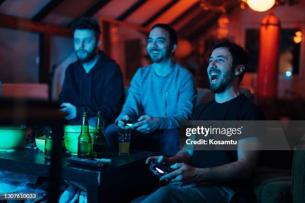 vrienden schreeuwen en juichen tijdens het spelen van de game battle op de playstation - playing sofa stockfoto's en -beelden