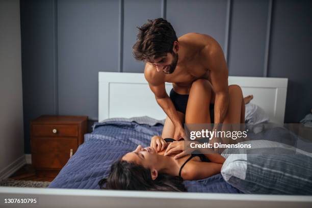glückliches junges paar hat spaß im bett. die gesellschaft des anderen genießen - kissenschlacht paar stock-fotos und bilder