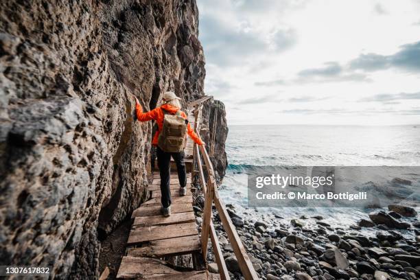 woman walking on an uneven coastal pathway - passerelle voie pédestre photos et images de collection