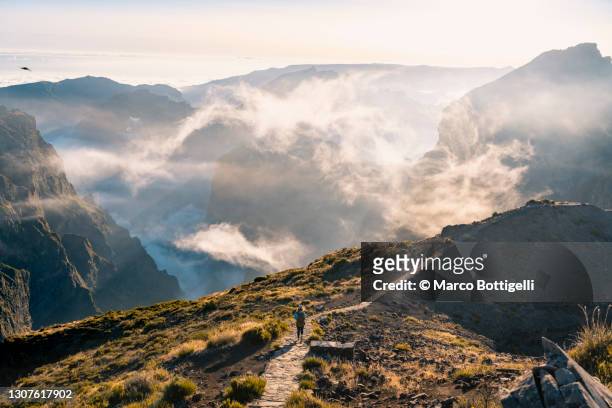 tourist walking on a footpath on a mountain ridge in madeira - pico do arieiro fotografías e imágenes de stock