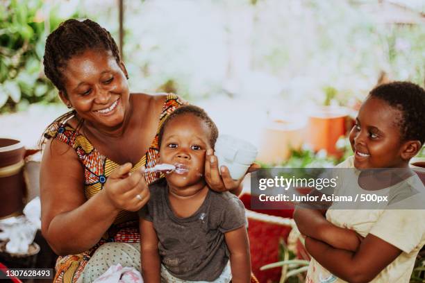 smiling african mother and feeding young boy,ghana - ghanaian family bildbanksfoton och bilder