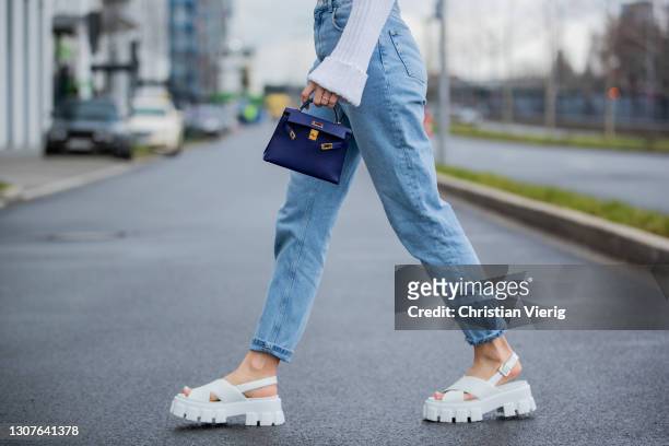 Ann-Kathrin Götze is seen wearing copped white jumper Zara, denim jeans Saint Laurent, white shoes Prada, purple bag Hermes on March 17, 2021 in...