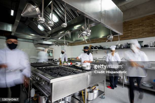 chef working in a kitchen wearing facemask during the pandemic - blurred motion effect - food and drink industry stock pictures, royalty-free photos & images