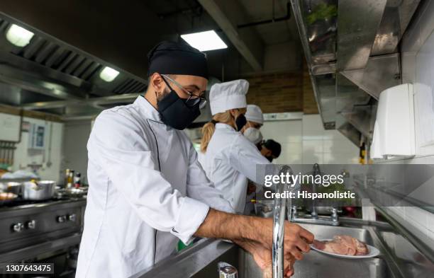 chef washing his hands in the kitchen while wearing a facemask - disinfection school stock pictures, royalty-free photos & images