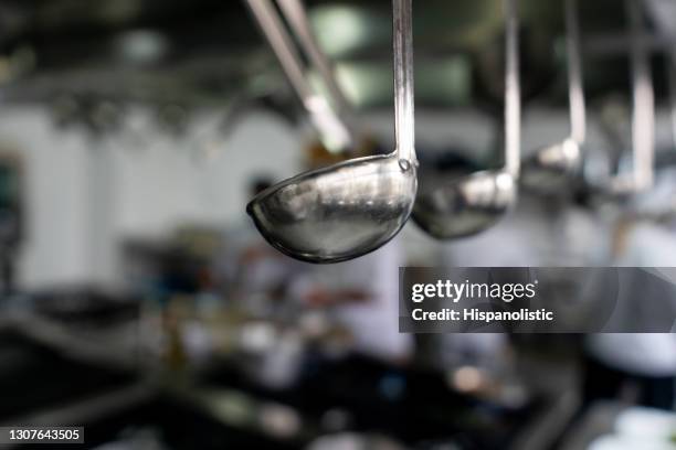 utensili da cucina appesi in una cucina commerciale - mestolo foto e immagini stock