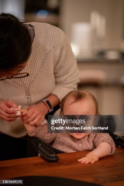 mom cleaning her baby's hand with tissue - baby wipes stock pictures, royalty-free photos & images