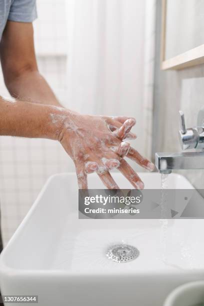 anonieme jonge mens die zijn handen met zeep en water thuis wast - hand wash stockfoto's en -beelden