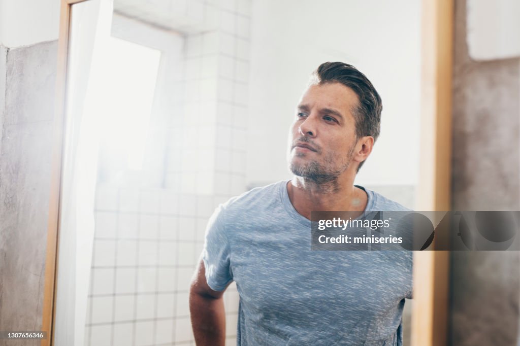 Handsome Young Man Checking his Beard in a Bathroom Mirror