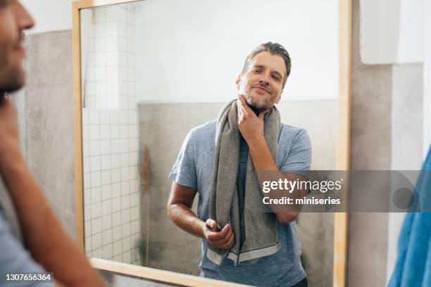 handsome young man trockin mit einem handtuch im badezimmer - man shaving face stock-fotos und bilder