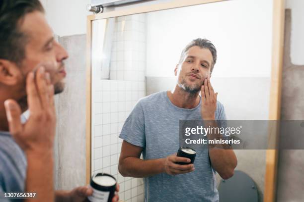schöne junge mann anwendung gesichtscreme nach einem morgen shave - mann creme stock-fotos und bilder