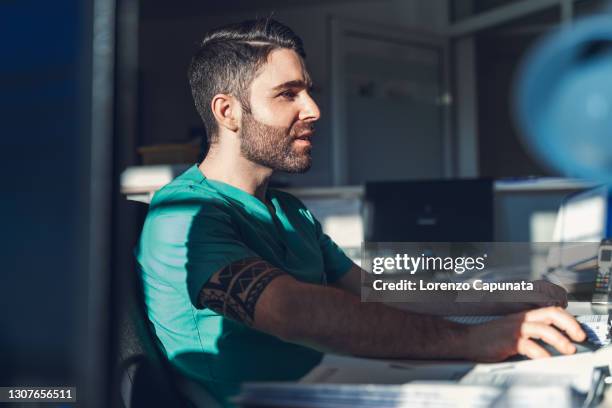 nurse. with face illuminated by a ray of sunlight, works at computer. - saxony stock-fotos und bilder