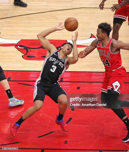 Keldon Johnson of the San Antonio Spurs looses control of the ball after injuring his ankle driving against Wendell Carter Jr. #34 of the Chicago...