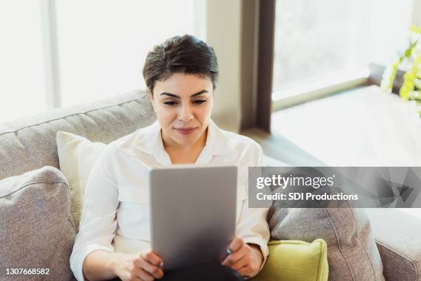 woman uses digital tablet to watch movie at home - office space movie stock pictures, royalty-free photos & images