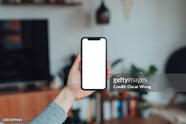 mockup image of woman holding smartphone with blank white screen at home - twitter template ストックフォトと画像