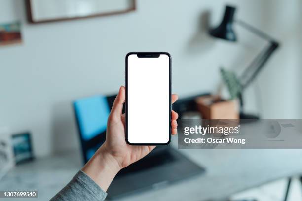 mockup image of woman holding smartphone with blank white screen at home - hand stock pictures, royalty-free photos & images