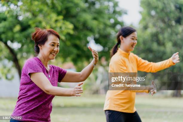 asian chinese mother and daughter doing tai chi exercise at public park - tai chi stock pictures, royalty-free photos & images