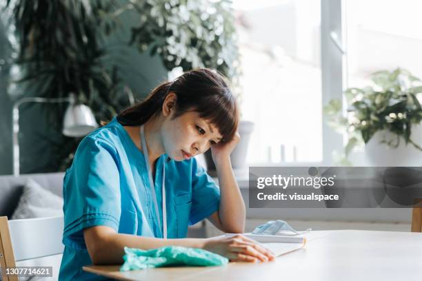 overworked and stressed asian nurse after long workday - sad nurse stock pictures, royalty-free photos & images