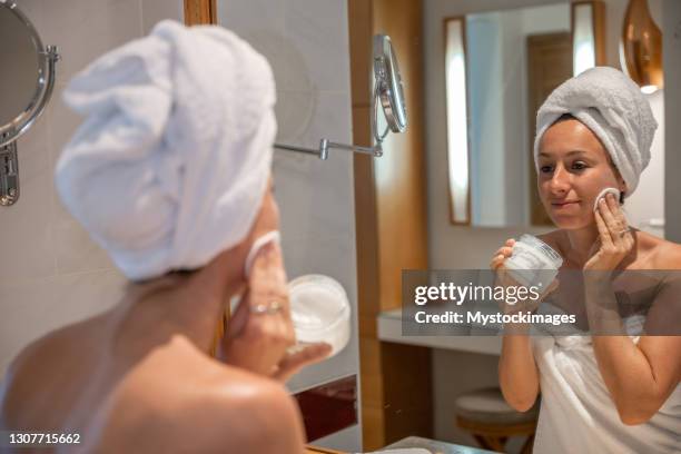 femme dans la salle de bains nettoyant vers le haut de la peau avec le disque de coton - huile de coco photos et images de collection