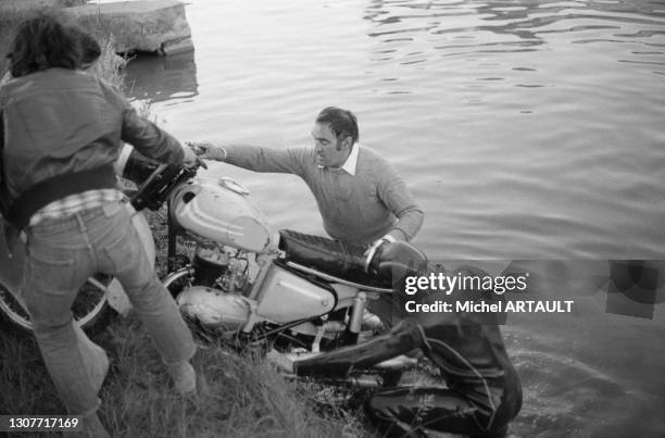 Le cascadeur Rémy Julienne sort sa moto de l'eau après une cacade sur le tournage du film 'La Gifle' à Senlis le 11 juin 1974.