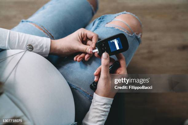 pregnant woman testing blood sugar at home - baseline stock pictures, royalty-free photos & images