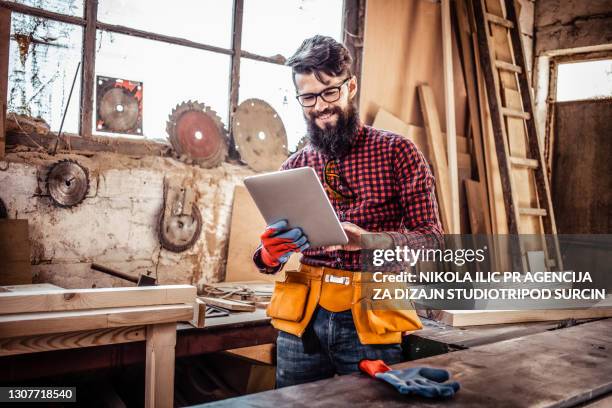 junger mann in der schreinerei schneidet holz mit einer kreissäge und mit digitalen tablet. - schreiner tablet stock-fotos und bilder